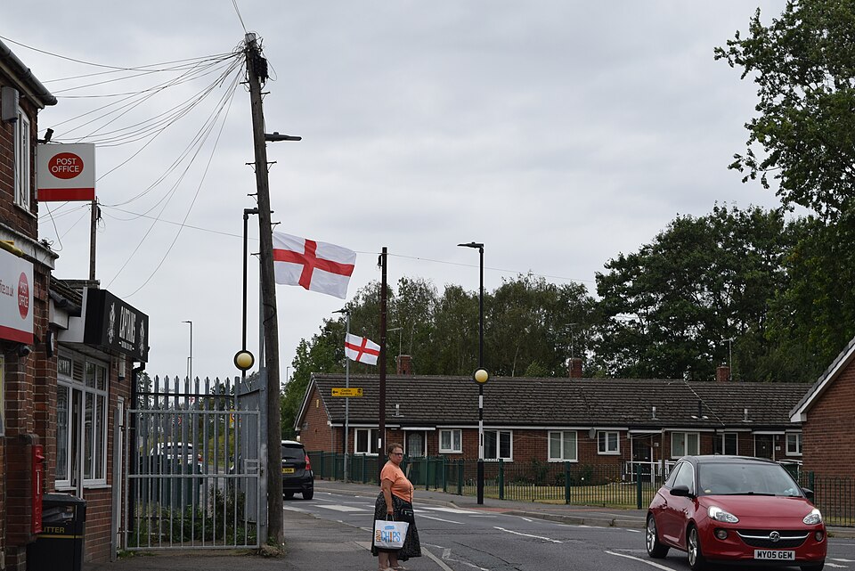 A suburban English street with St George's Cross flags on lamposts. 