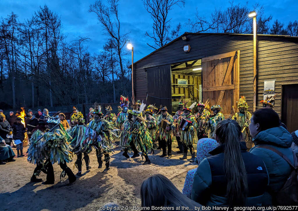 Wassailers emerge from a shed beside a wood