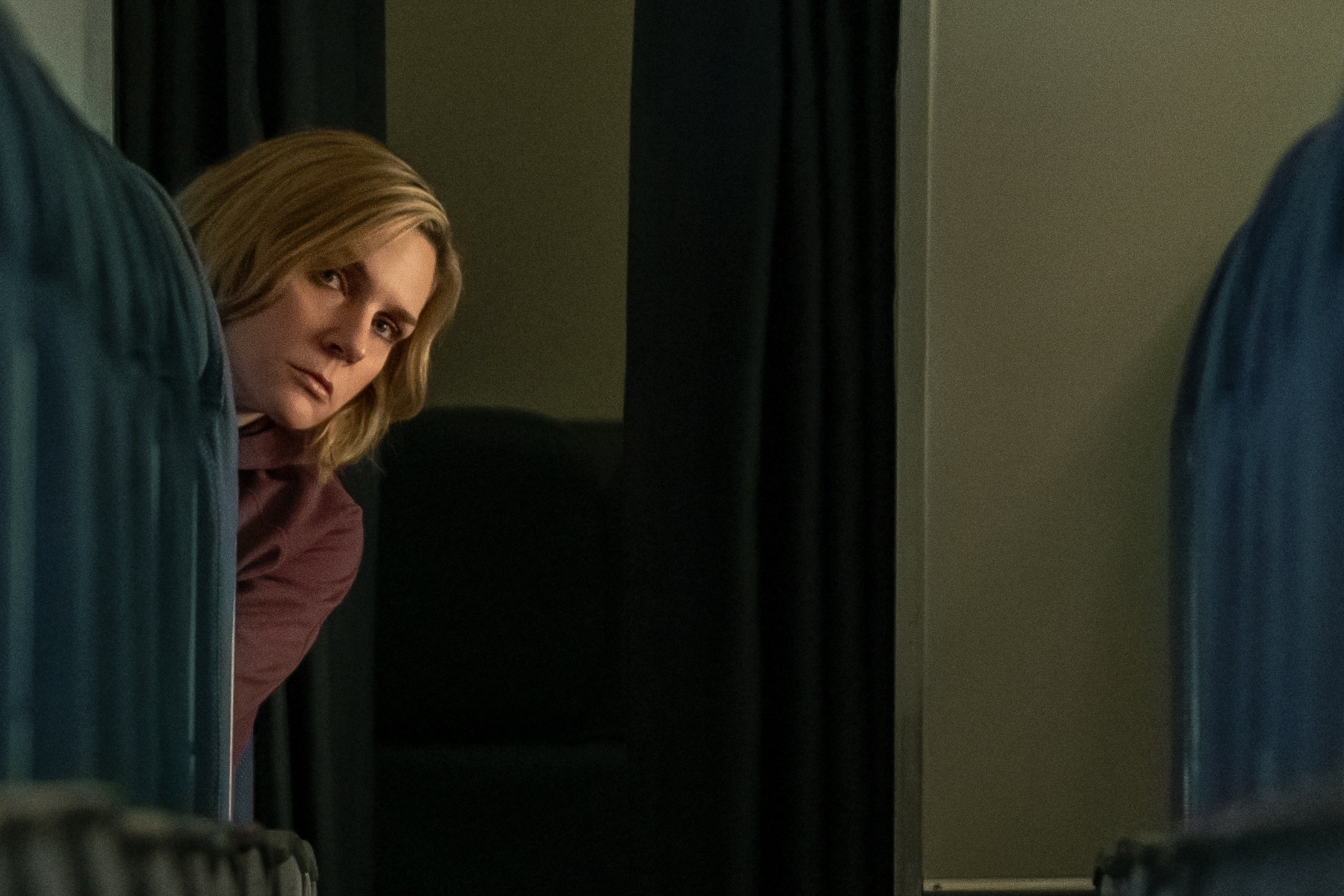 A passenger oeers out and down the aisle of an empty plane.