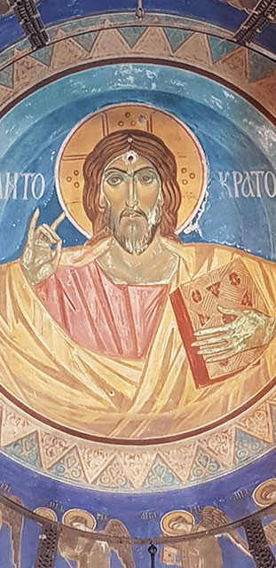 A mural depicts an icon of Christ with a bullet hole in his forehead.
