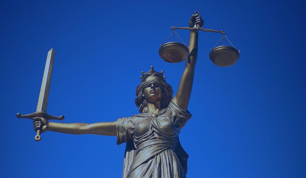 A statue of Justice holds a sword aloft in one hand, and set of scales in the other.