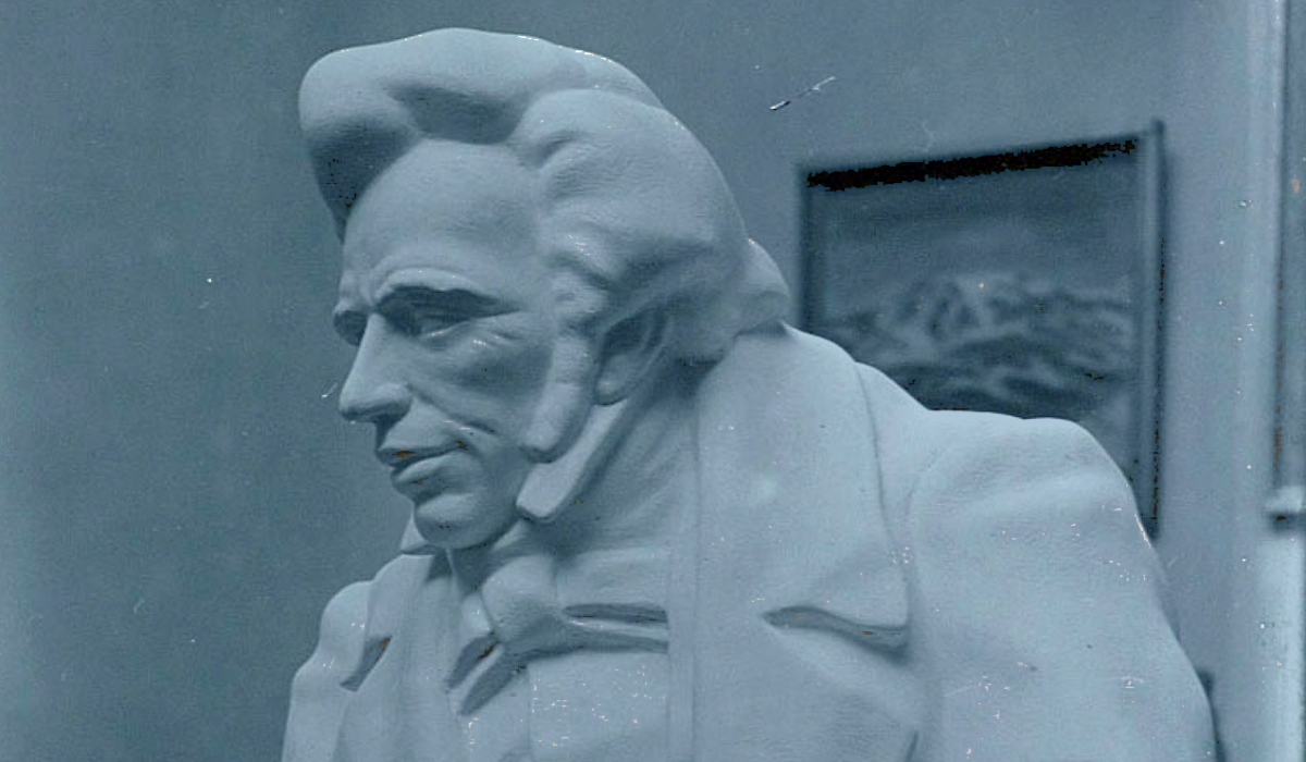 A sculpture of a early 19th century man with a quiff and sharp suit.