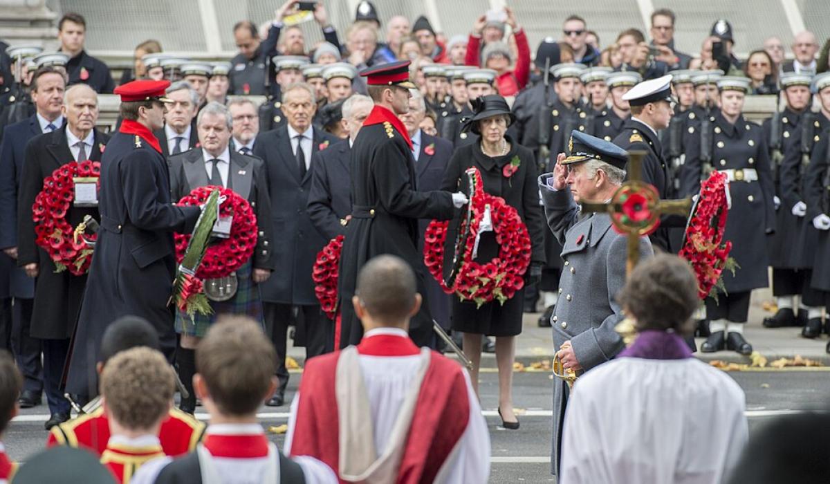 Princes and army officers walk away from a war memorial while others look on.