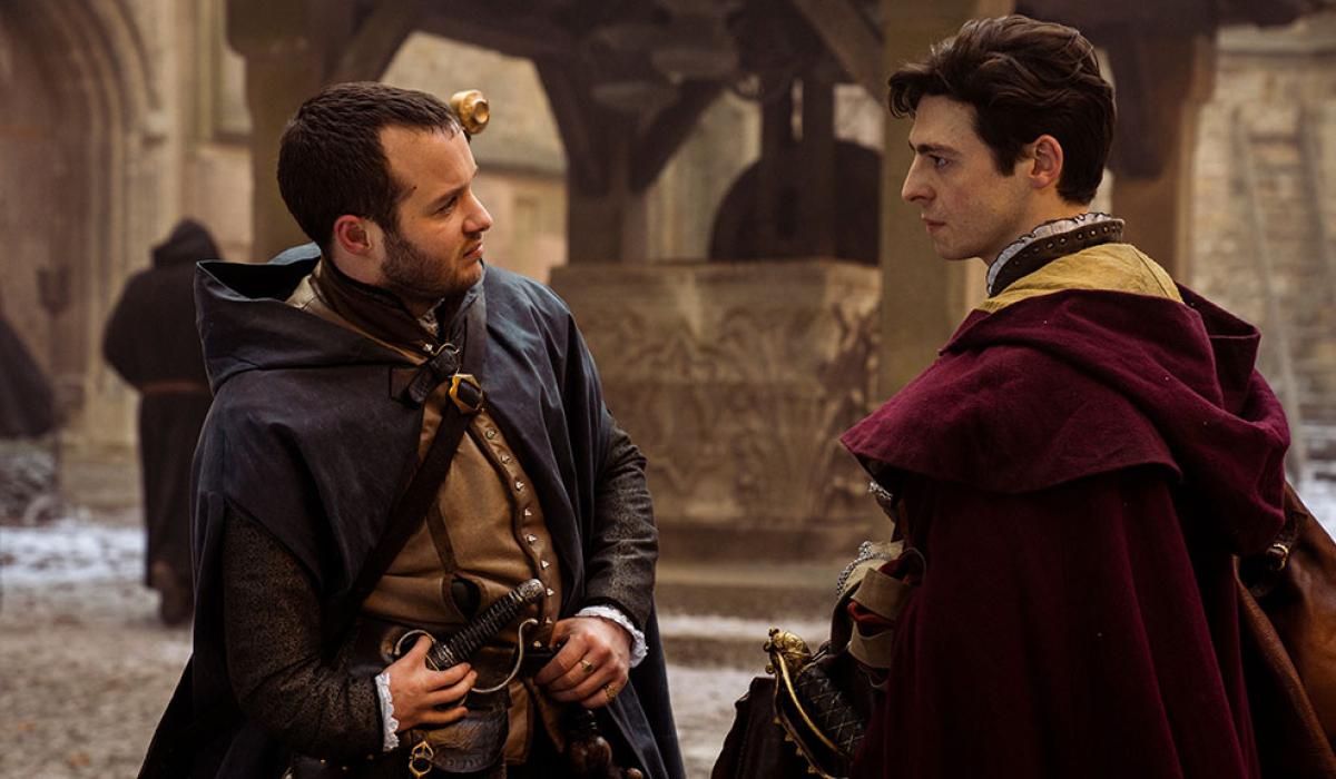 Two men in Tudor clothing converse in a street