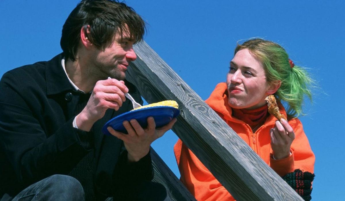 A coupe sit on outdoor steps against a blue sky. One holds a plate and the other looks towards them.
