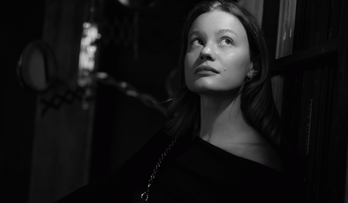 A black and white picture shows a woman head and shoulders, she is looking up and to the side in an unsure way.