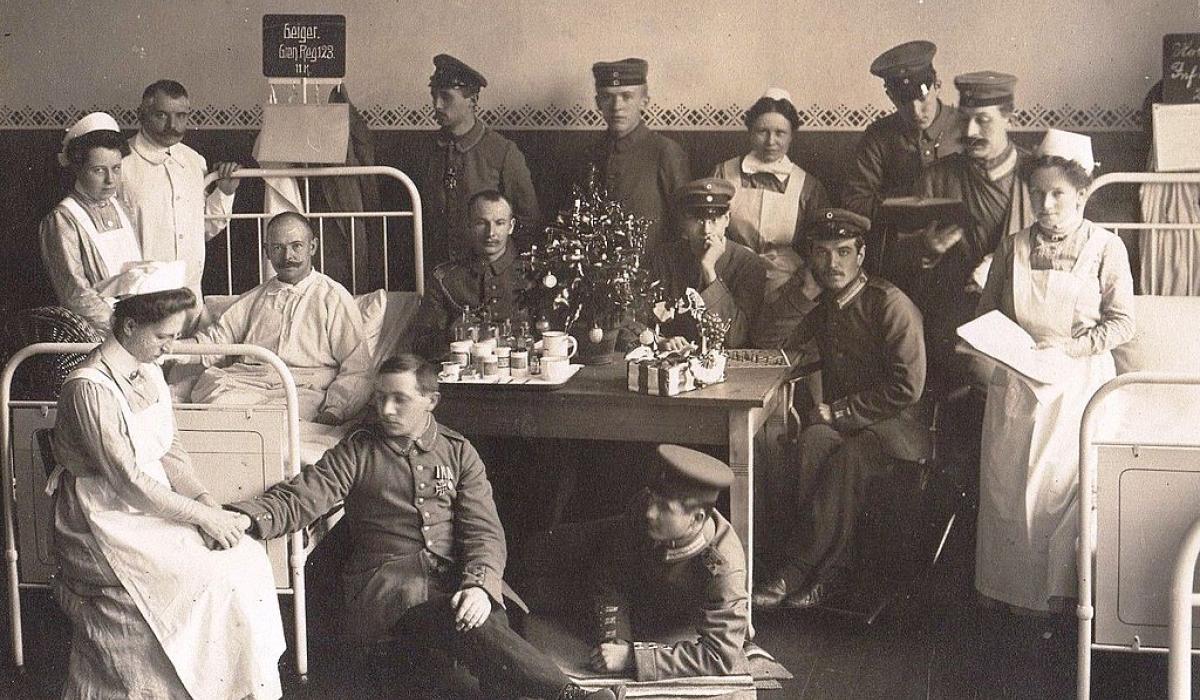 A black and white photo shows solider patients and nurses in a hospital.