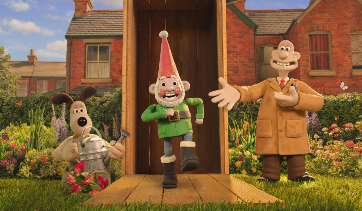 A still from a claymantion film shows three characters, Wallace, Gromit and a robot garden gnome marching out a garden shed.