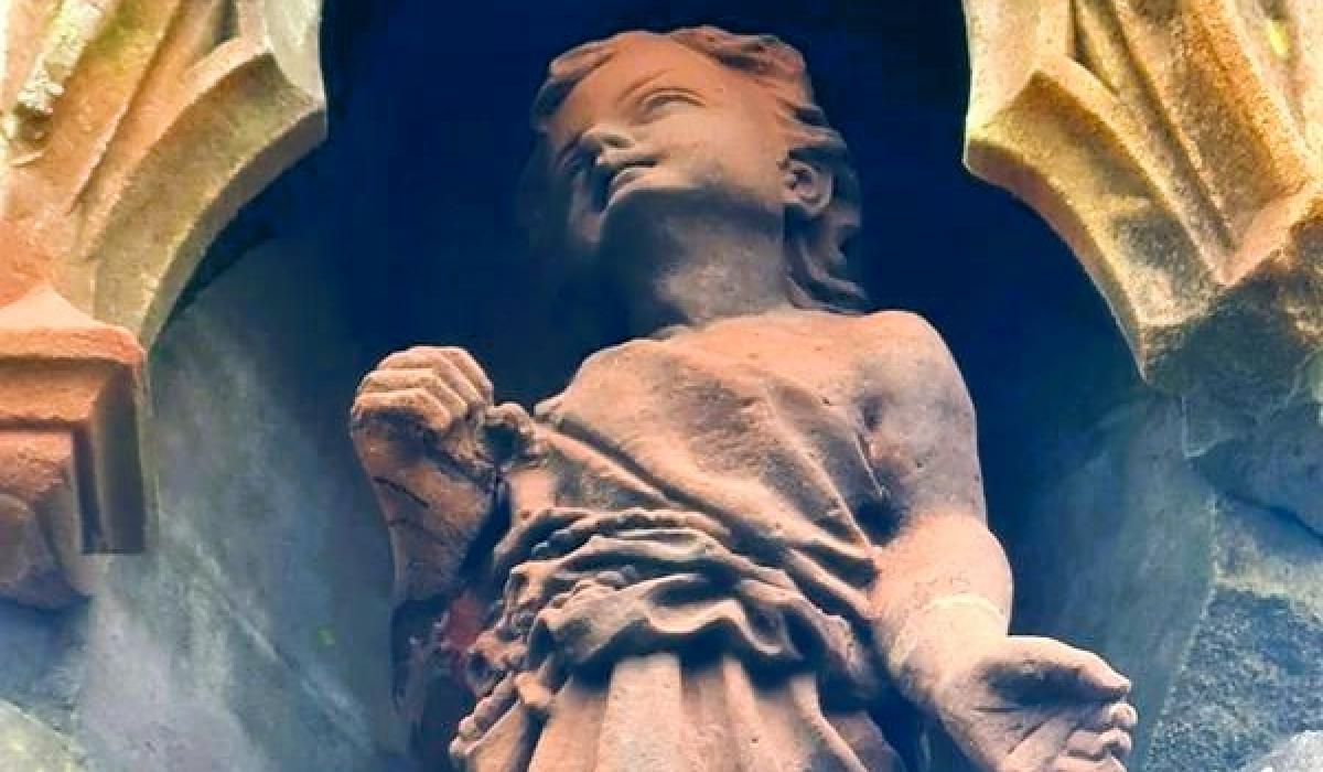 A red sandstone statue of Jesus as a child.