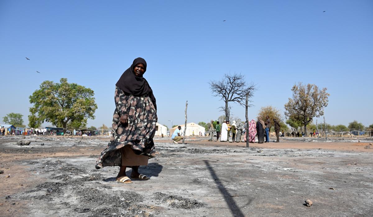 A Sudanese woman walks across the ashes of a burnt out street market.