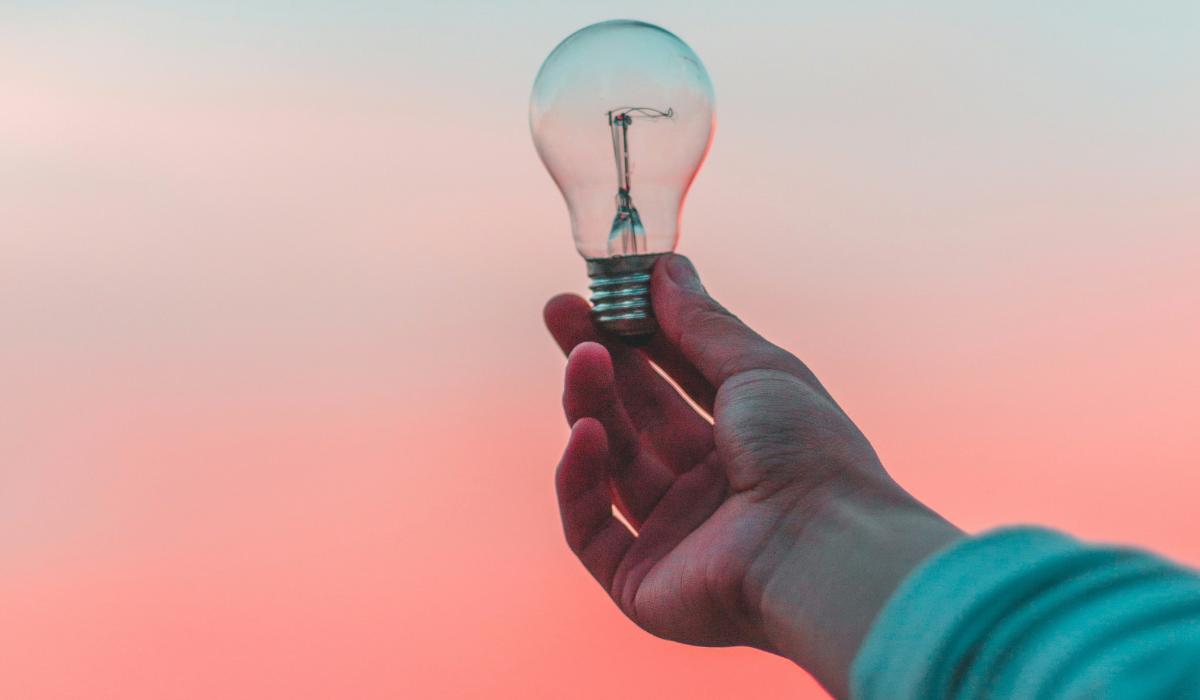 A light bulb is held up against a sunset.