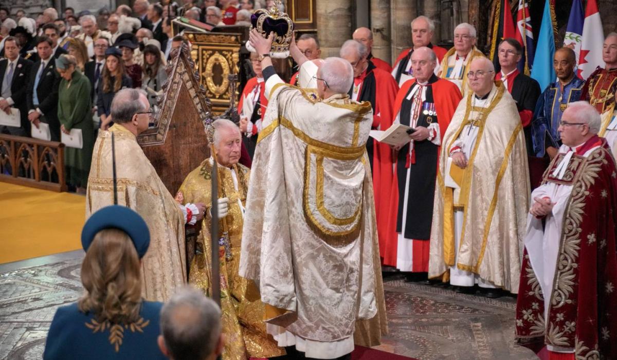 An archbishop raises a crown about the head of King Charles.