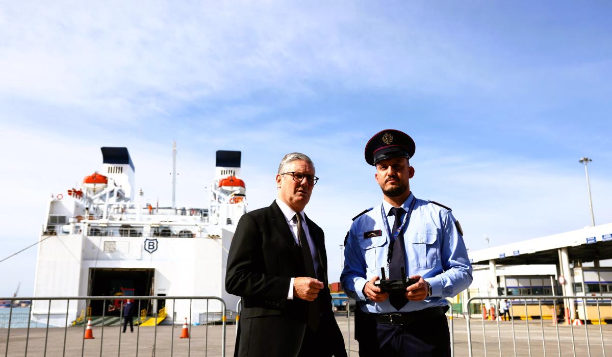 A prime minister stands next to an Albanian police officer in front of a ferry.