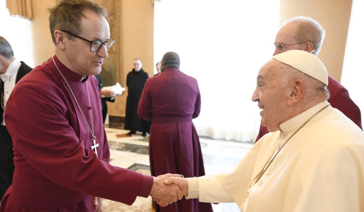 An Anglican bishop wearing purple shakes hands with the Pope.