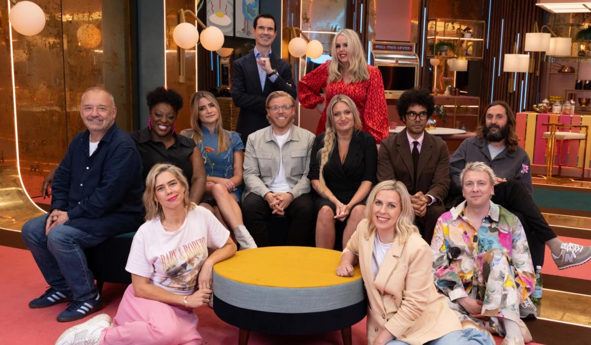 A group of comedians pose on a TV show set.