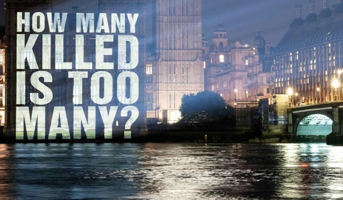 A sign projected on to the Houses of Parliament reads: how many is too many.