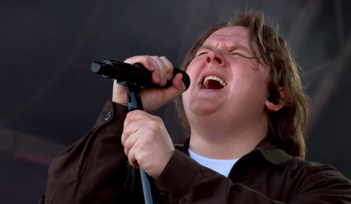Lewis Capaldi sings with eyes closes, holding a mic and its stand