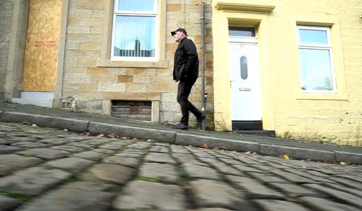 A man walks up a cobble street.
