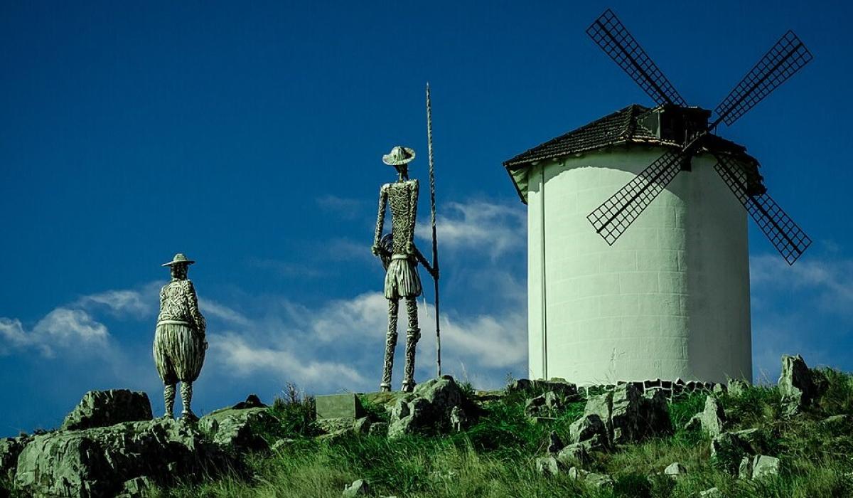 Statues of Don Quixote and Sancho Panza point toward a windmill