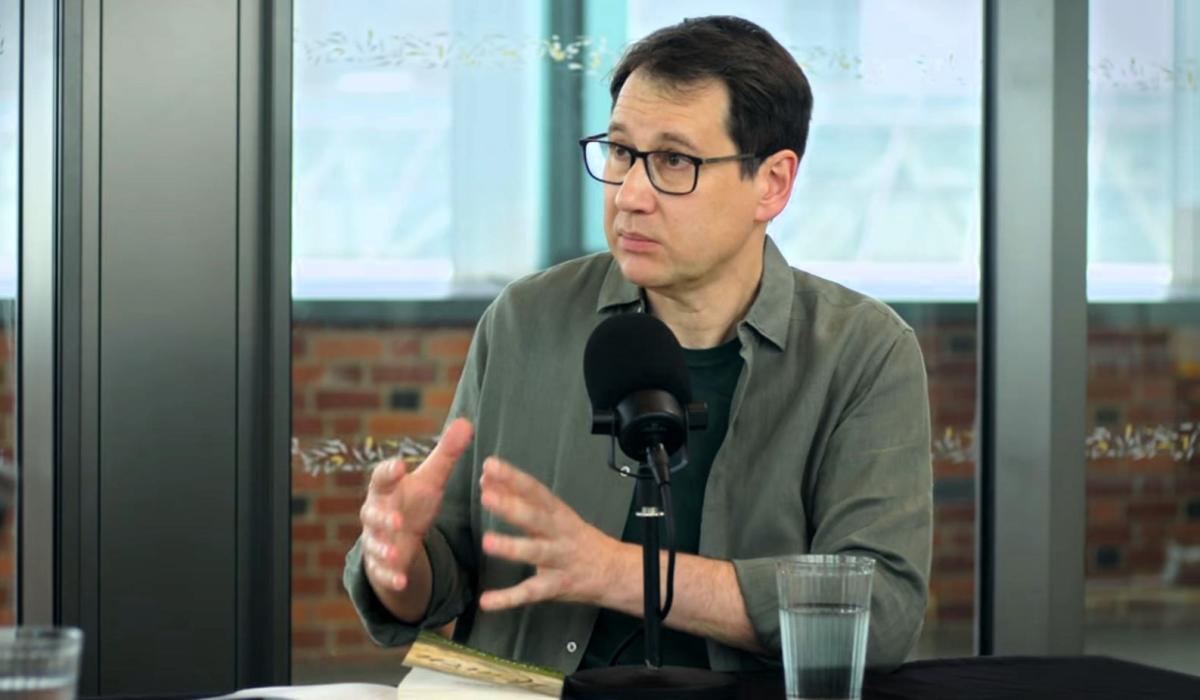 A podcast guest gestures with their hands.