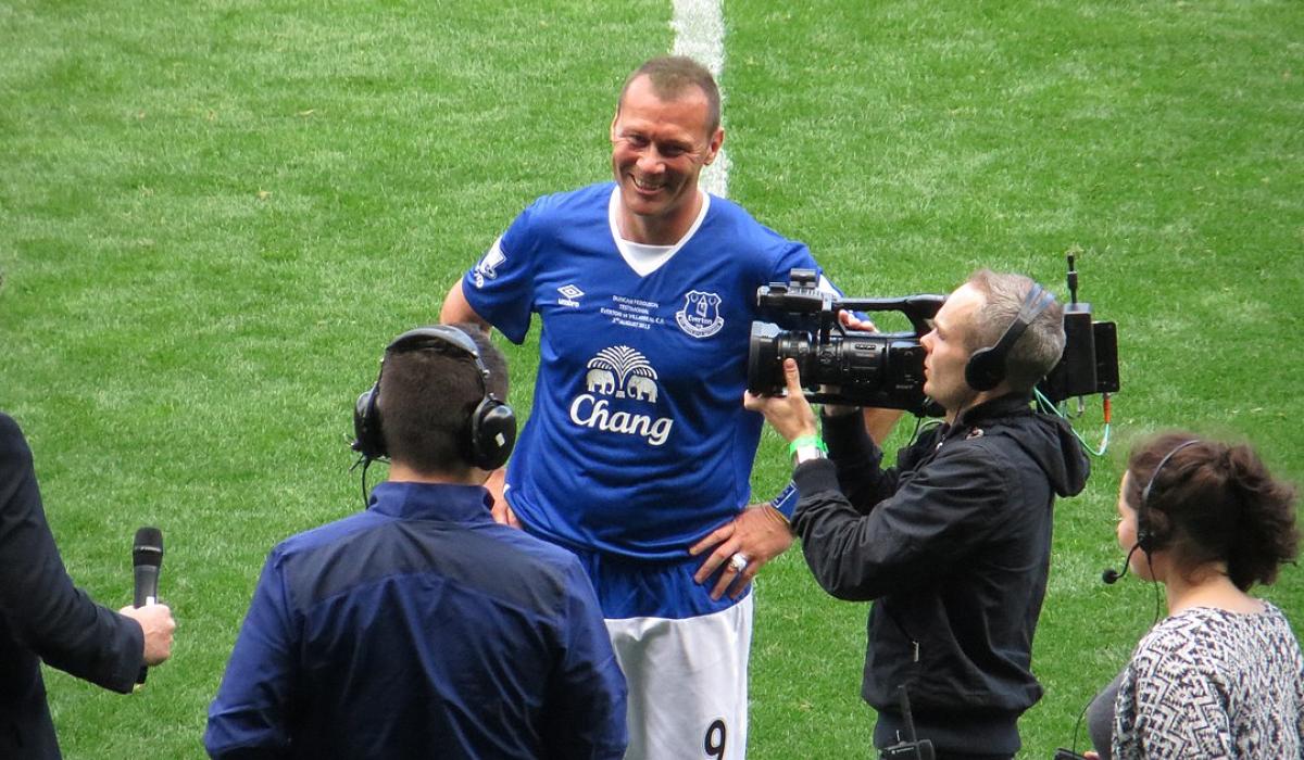 A footballer is interviewed on the side line.