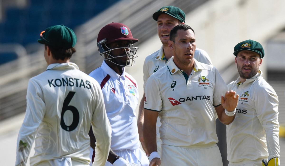 A cricket batsman surrounded by opposition players leaves the crease.
