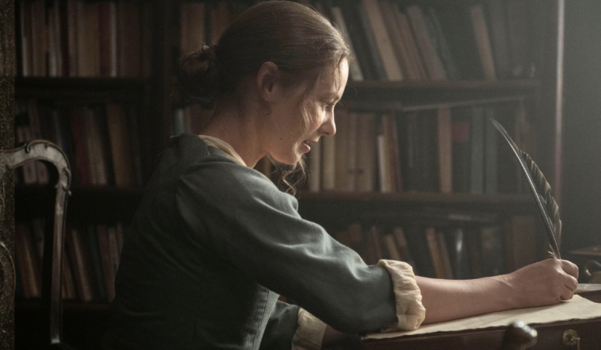 A regency woman writes with a quill