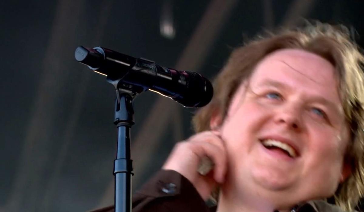 A singer leans back from the mic smiling