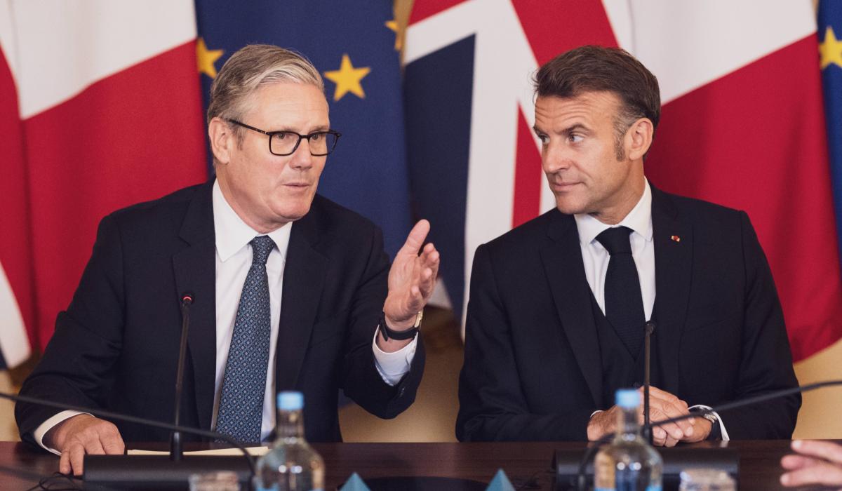 Keir Starmer and Emmanuel Macron in front of flags.