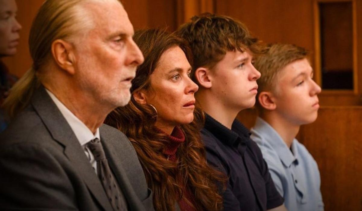 A family sit together watching a trial in a court.
