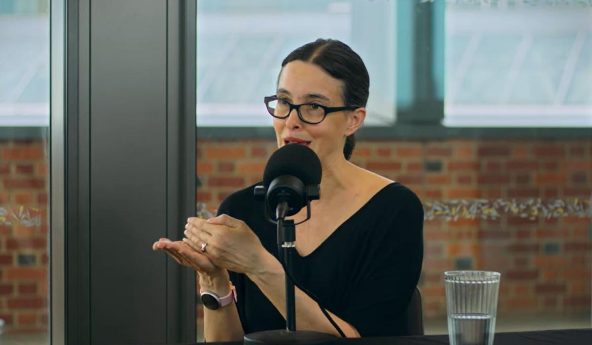 a woman speaks and gestures while recording a podcast