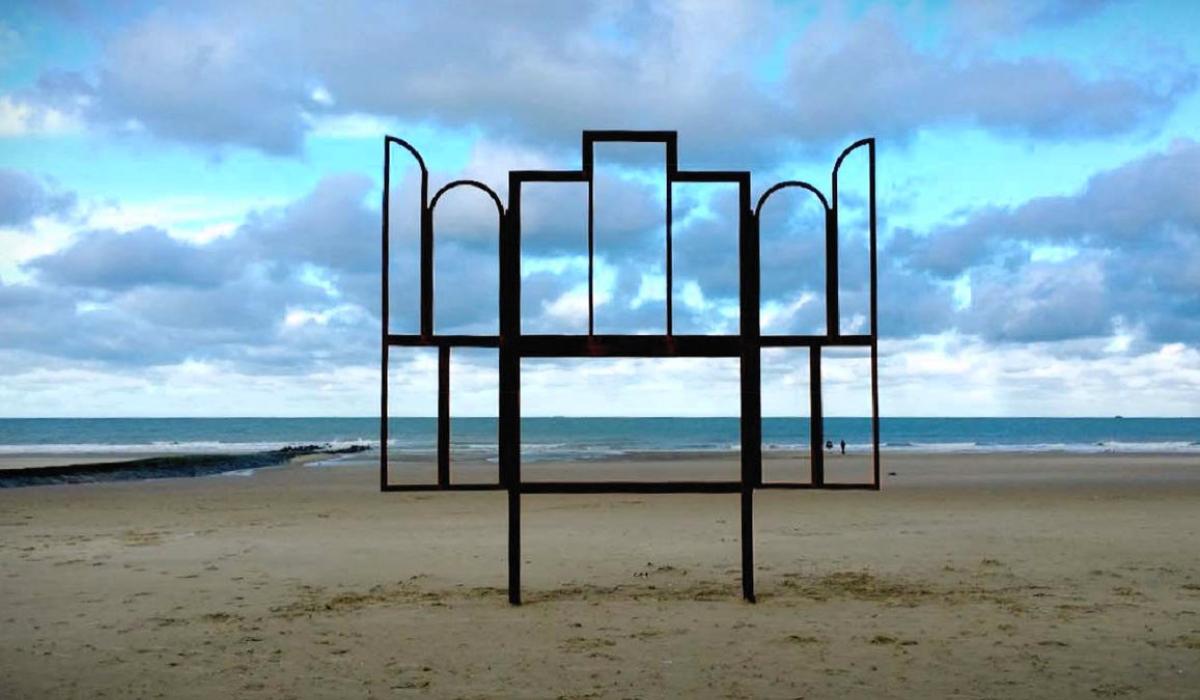 A metak sculpture outlines an altar, stands on a beach.