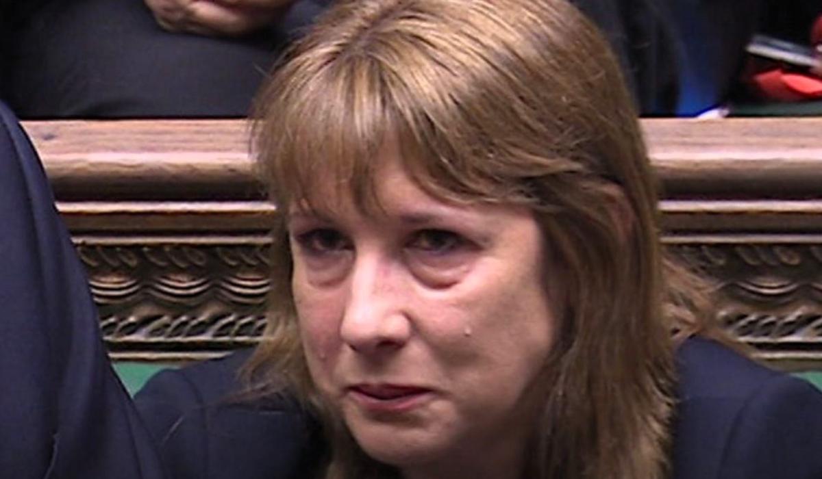 A woman sits and holds back a tear.