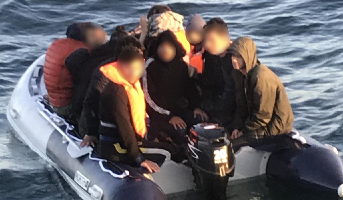 A people sumggler steers an overcrowded small boat.