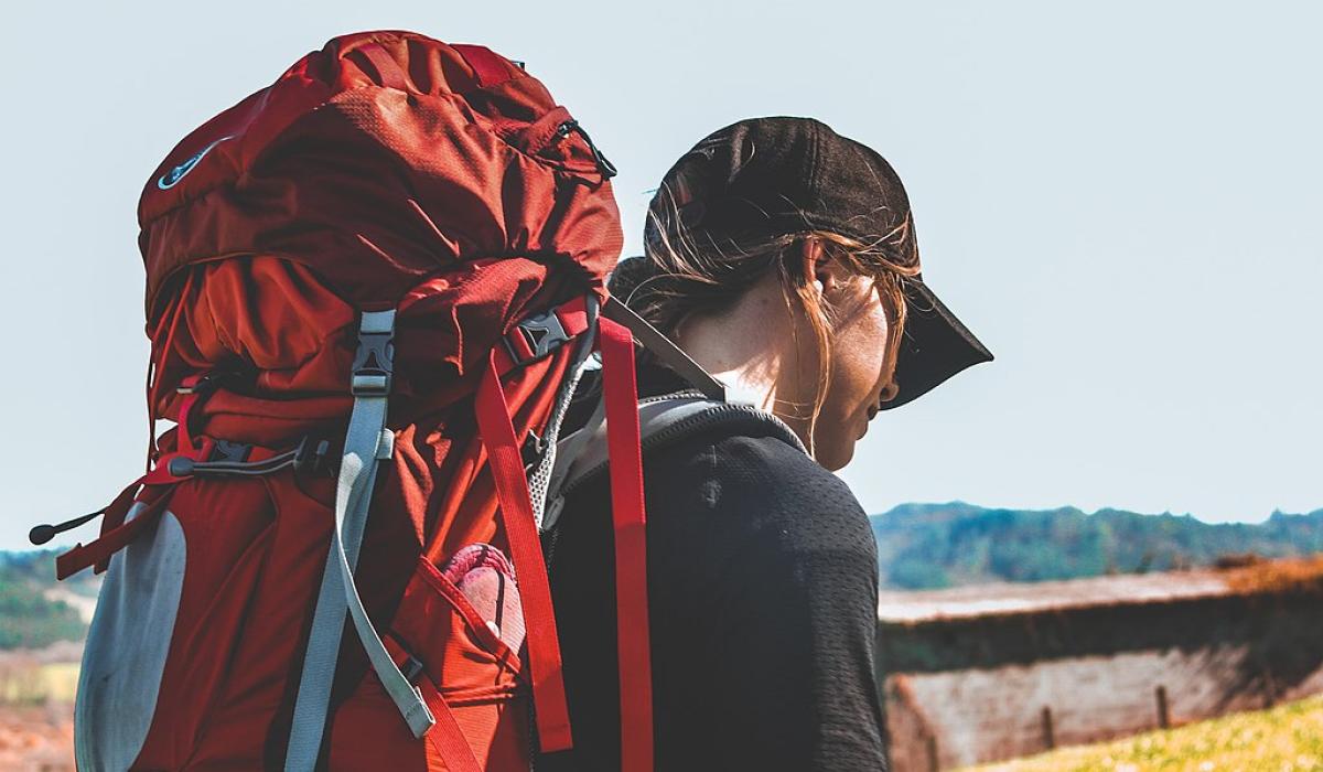 A pilgrim with a red backpack heads off.