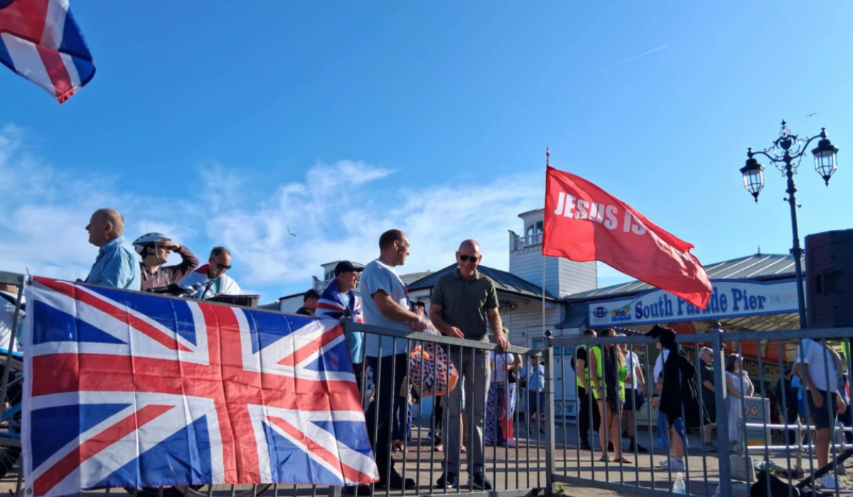 A Union Jack is draped over a railing, next to a red flag saying Jesus.