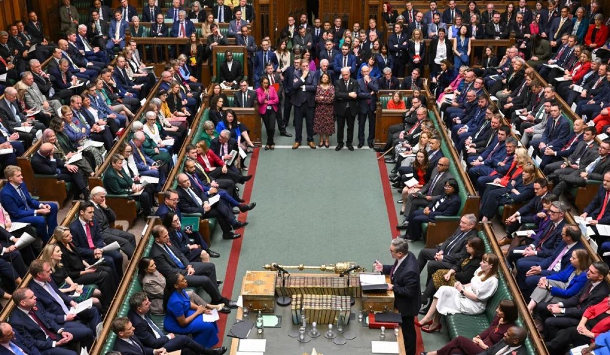 MPs sit and stand in a crowded parliament.