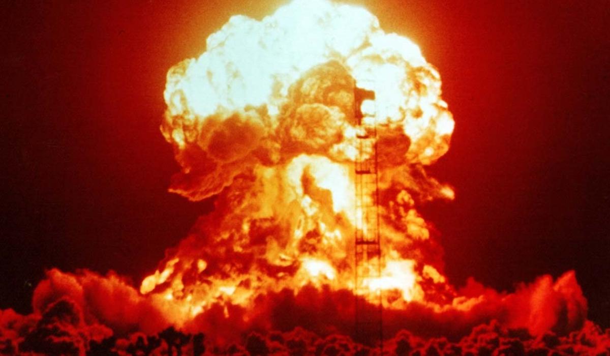 A nuclear explosion glows red and orange against the night sky.