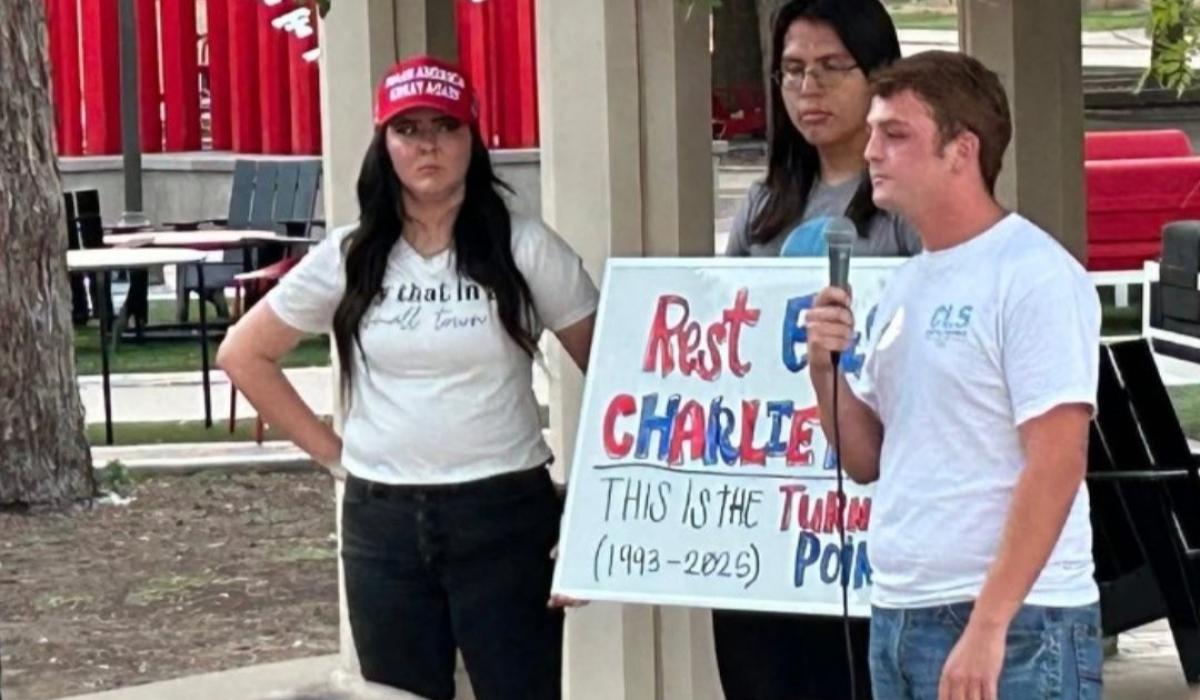 Mourning students at a vigil hold a sign about Charlie Kirk.
