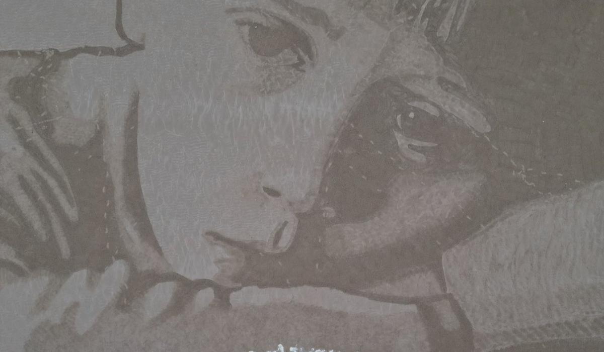 A sand drawing shows an unhappy child's face with the tide coming in from below