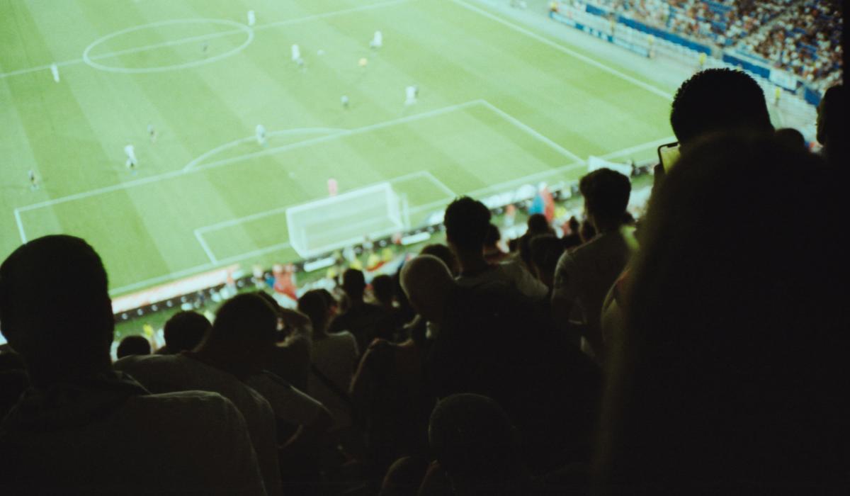 A view from a football stand over heads to the pitch.