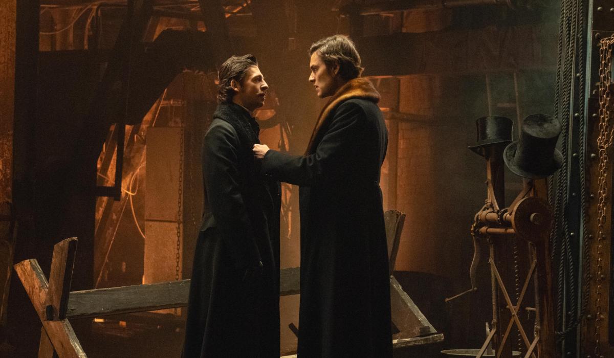 Two brothers look at each other in front of their ironworks.