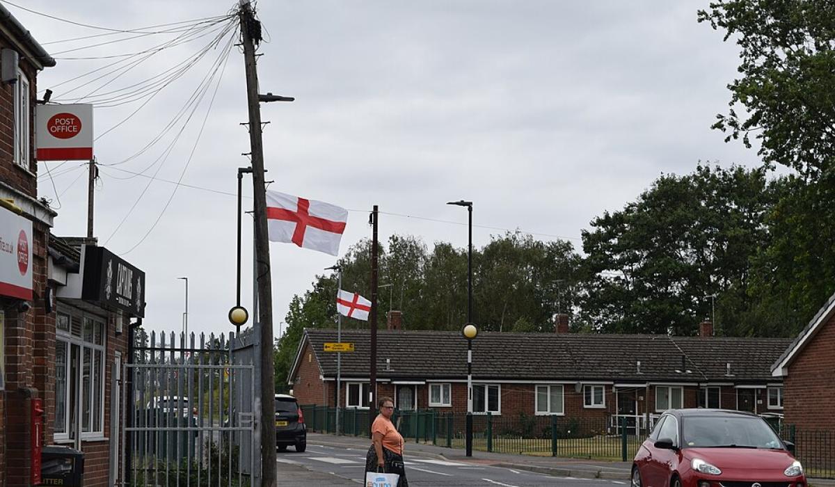 A suburban English street with St George's Cross flags on lamposts. 