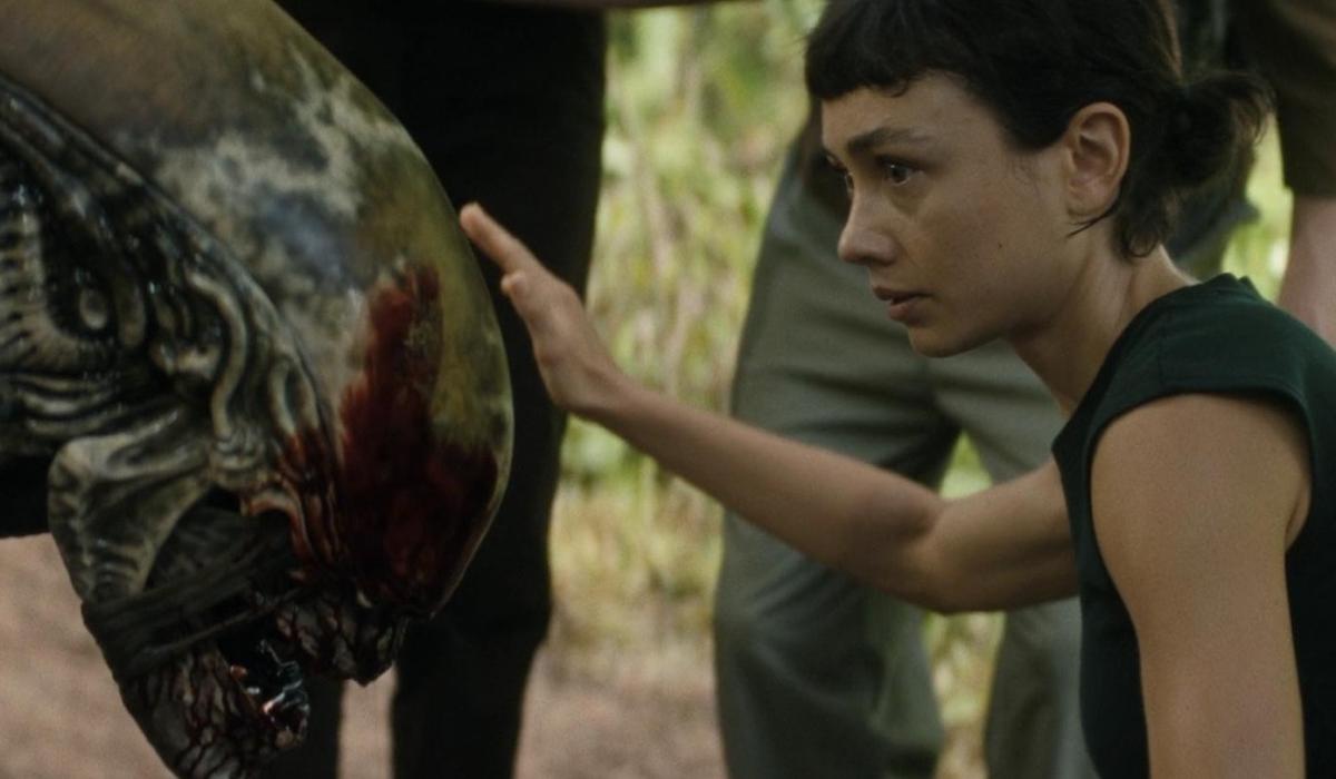 A young woman pets the head of an alien