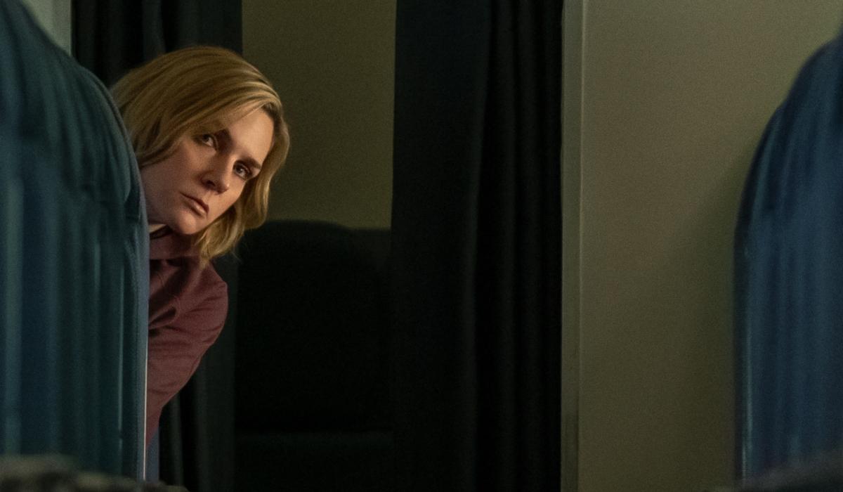 A passenger oeers out and down the aisle of an empty plane.