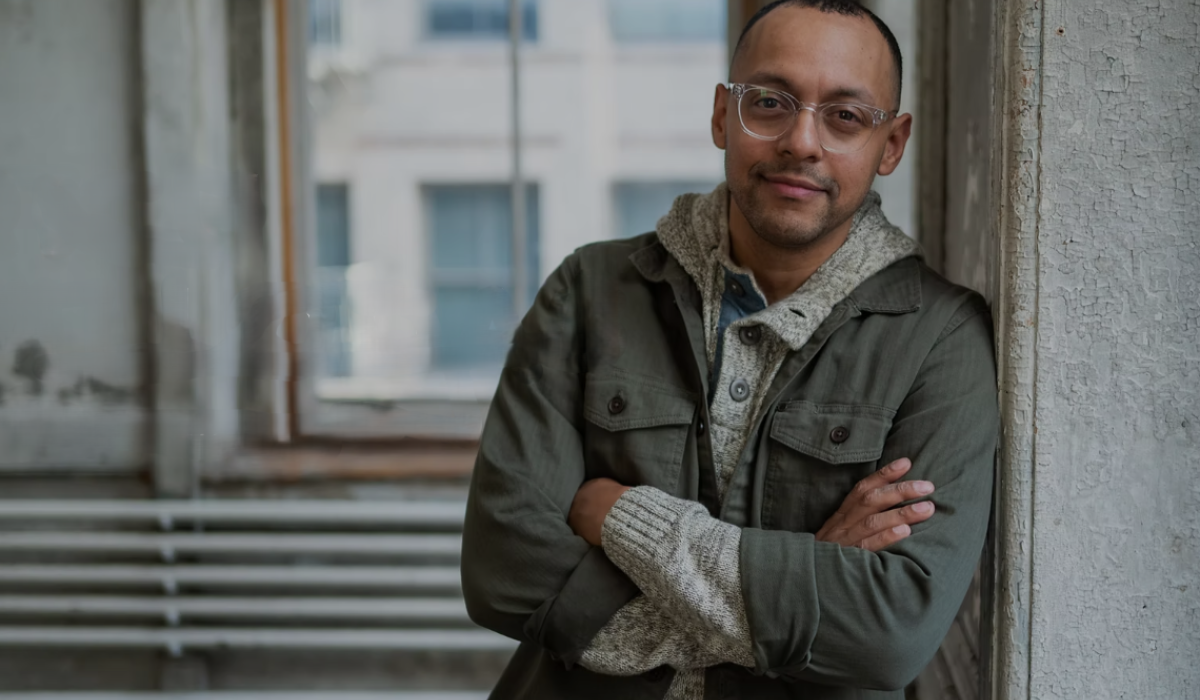 A man leans against a wall, arms folded.