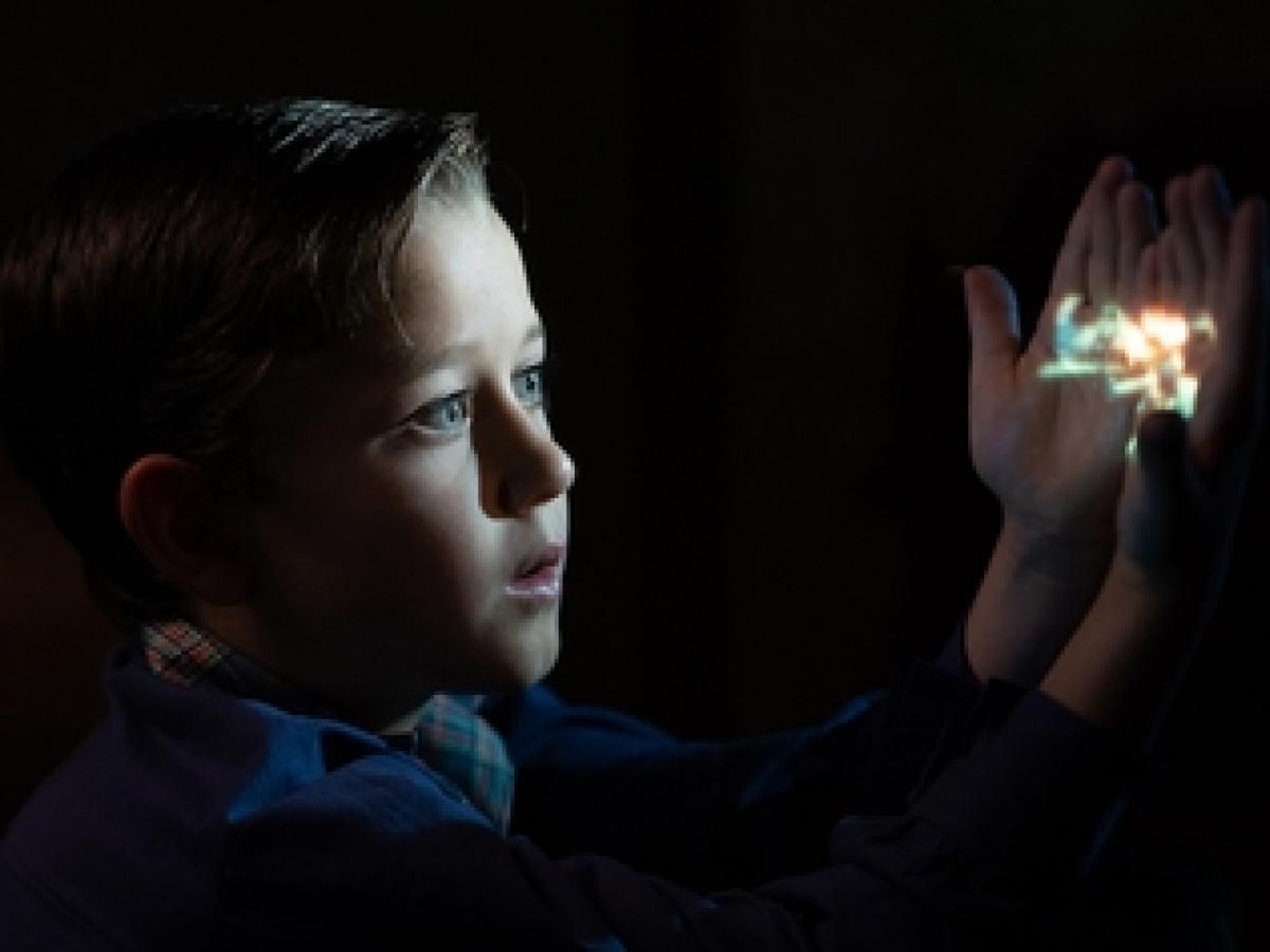 A cinematic view of a child holding an image that lights up their face.