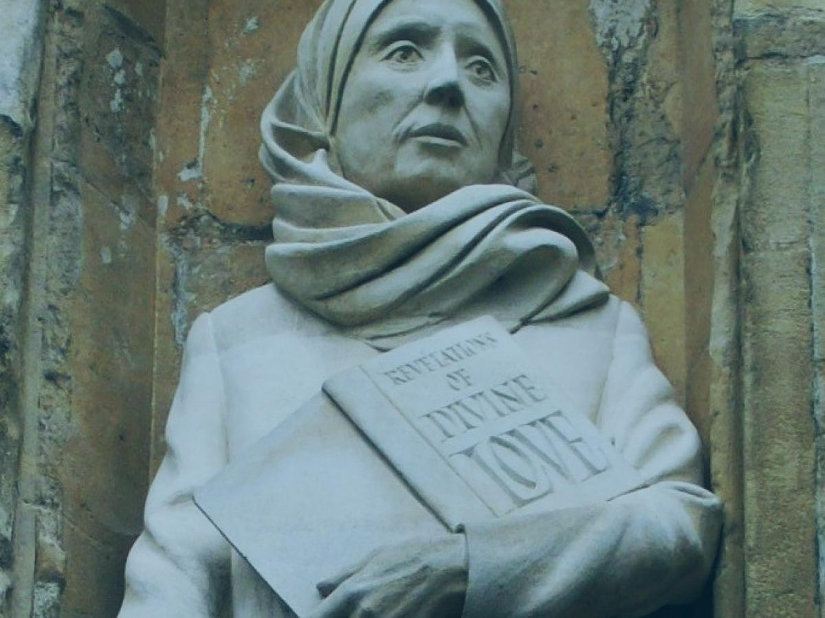 A statue of a Medieval women wearing a headscarf, and holding a book inscribed: revelation of divine love.o