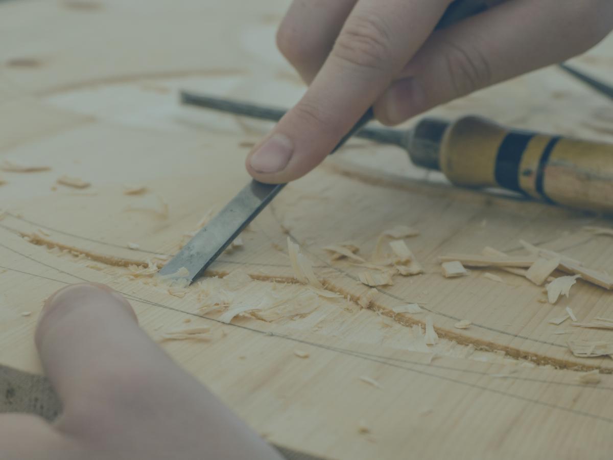 A carving tool is pressed into a groove in wood.