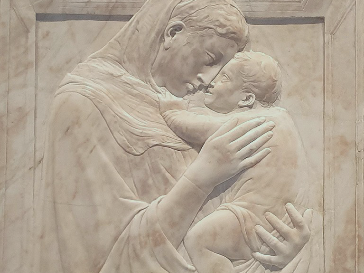 A relief sculpture shows the Madonna hold the infant Christ close to her face.